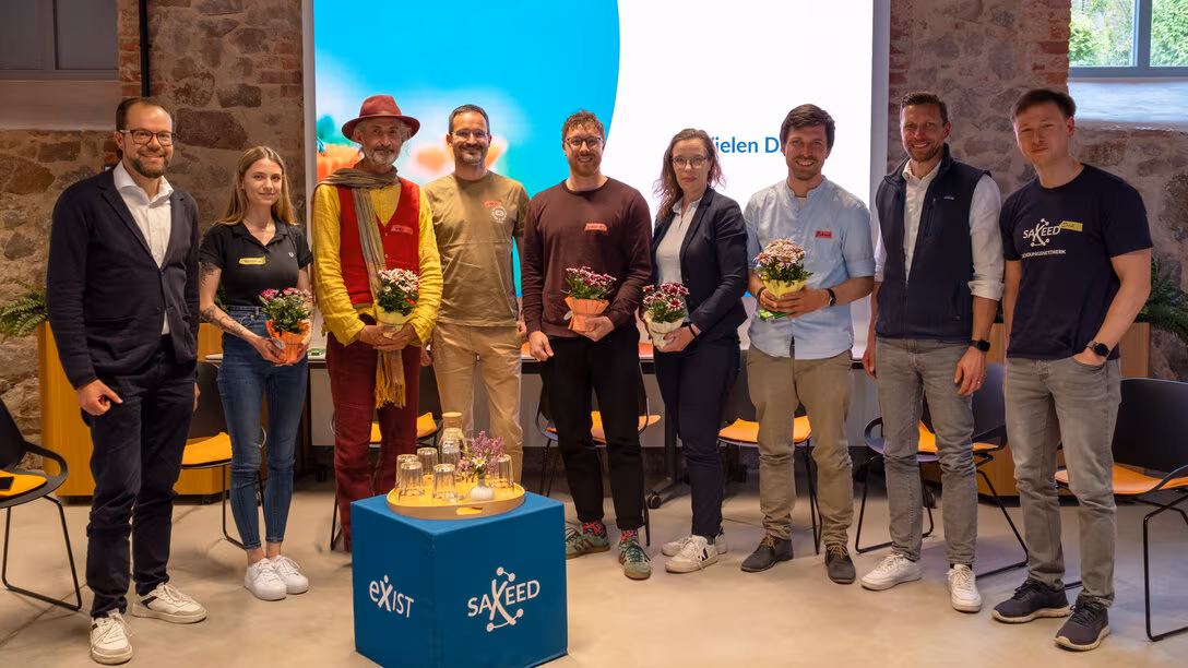 Gruppenaufnahme mit neun Personen. Einige von ihnen haben einen Blumentopf in den Händen.